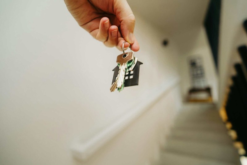 A person holding house keys while approaching a front door