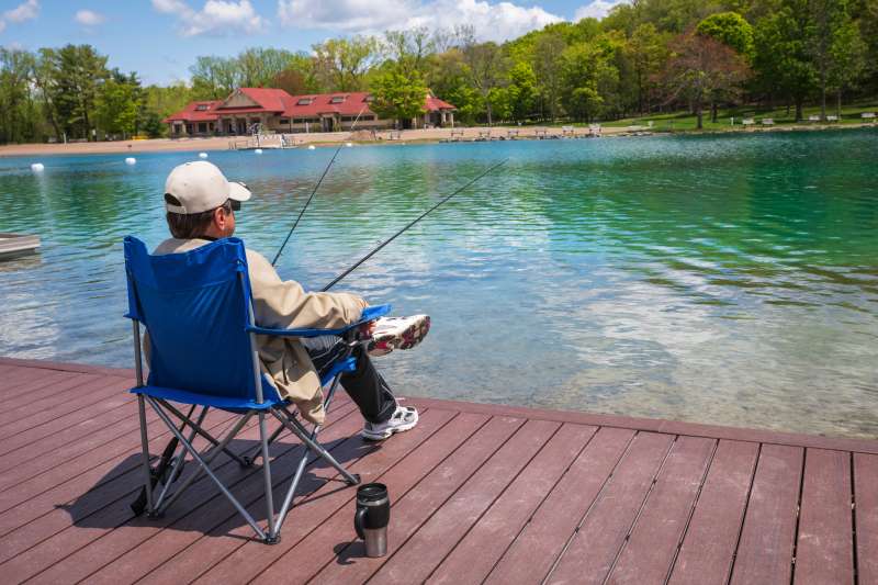 Man sitting on dock at Green Lakes State Park fishing in New York