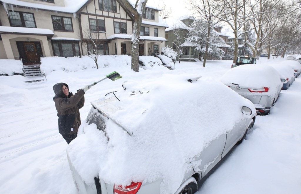 A woman shovels snow off her car, Winter forecast for New York
