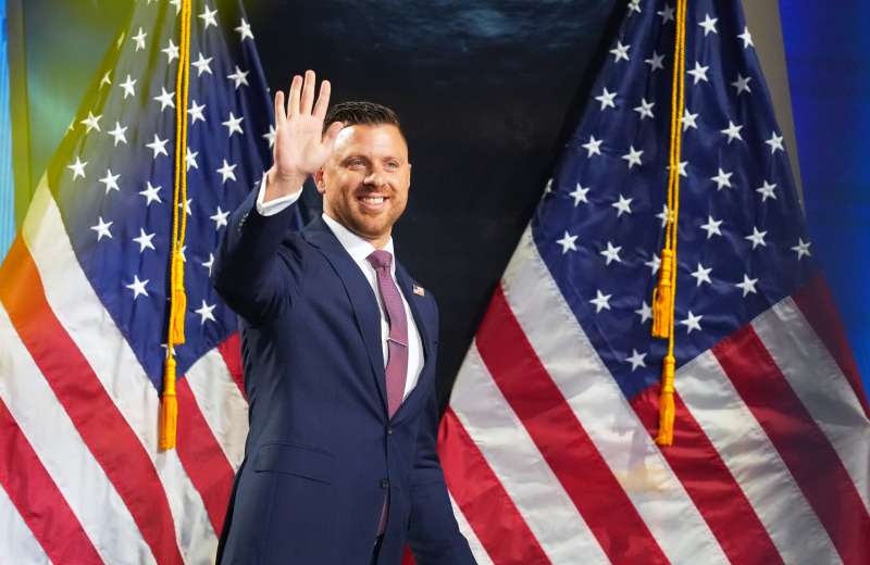 Mike LiPetri, the Republican challenging Rep. Tom Suozzi in NY-03, waves in front of American flags at the Republican convention in Dallas.