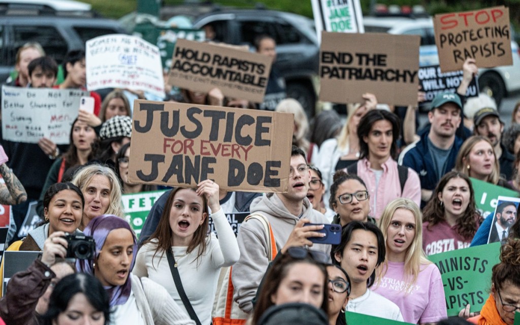 People hold signs while rallying against sexual violence